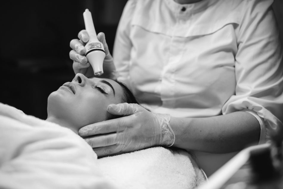 a technician giving a woman facial laser treatments
