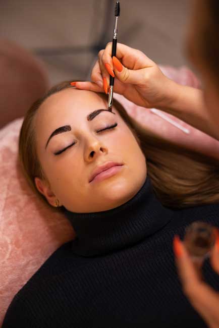 female-specialist-applying-dye-on-client-eyebrow